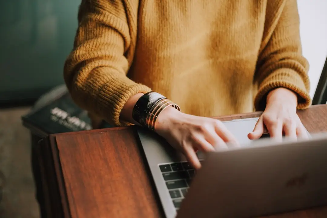Close-up of a person's hands typing on a laptop