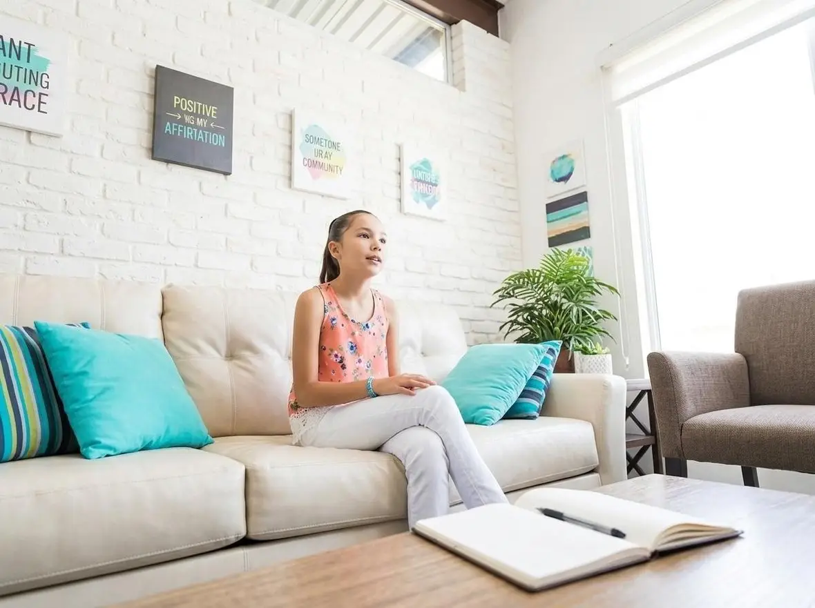 A person sitting on a sofa in a bright waiting room
