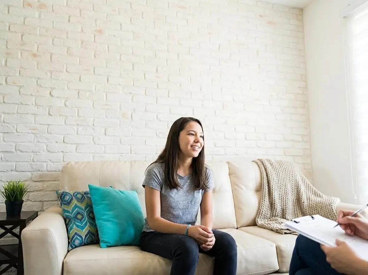 A person on a sofa talking with a clinician holding a clipboard