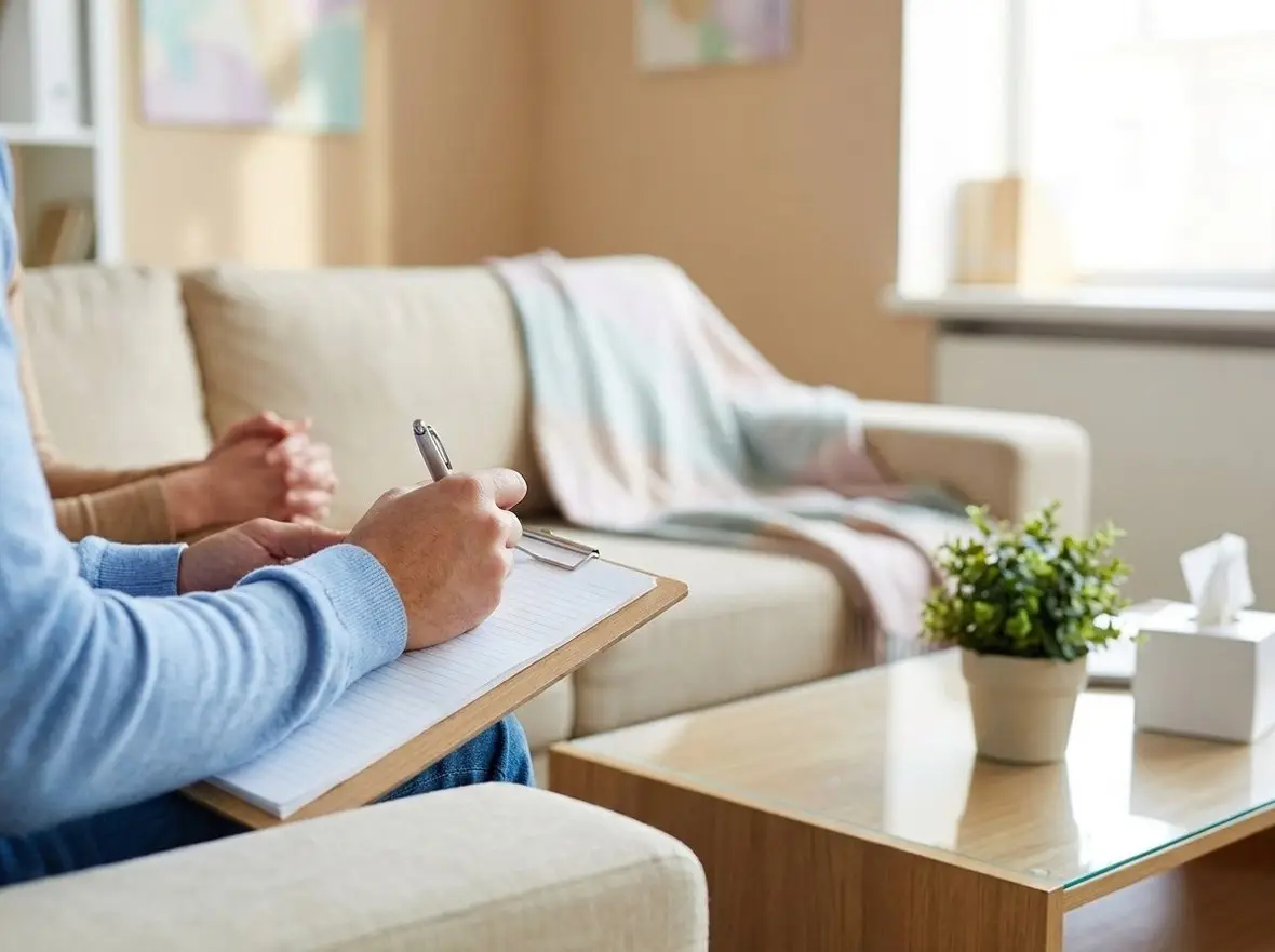 A clinician writing on a clipboard beside a sofa