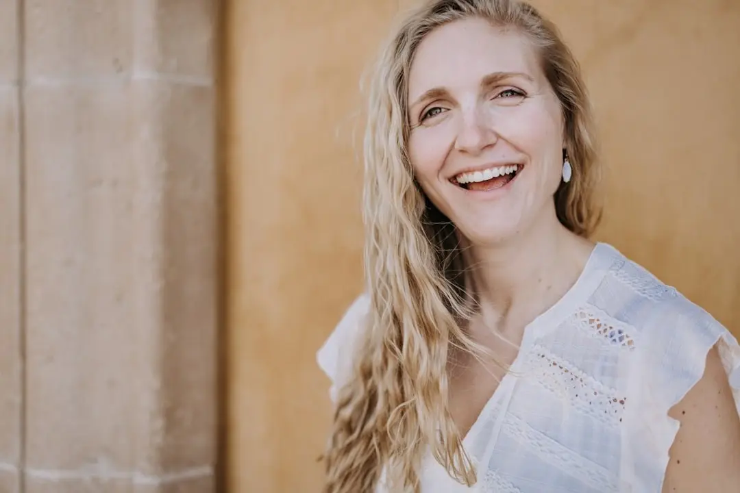 A person with long hair smiling outdoors