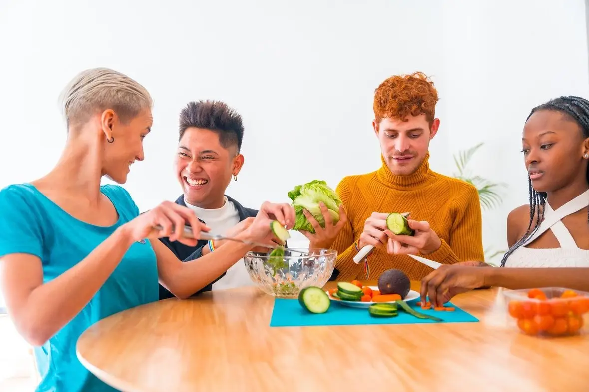 Friends preparing a fresh salad together at a table