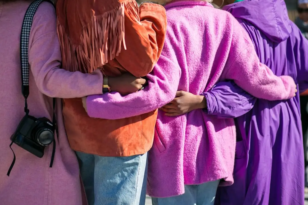 Friends in bright coats standing with their arms around each other
