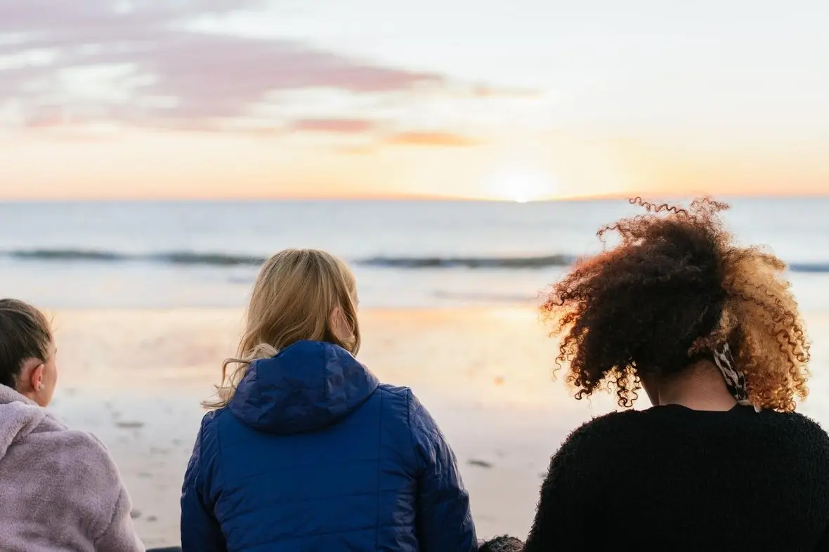 People looking out to sea at sunset