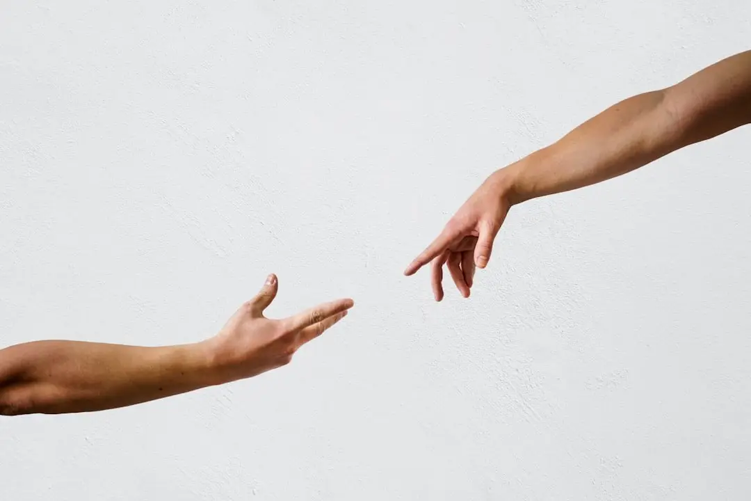 Two hands reaching toward one another against a plain background