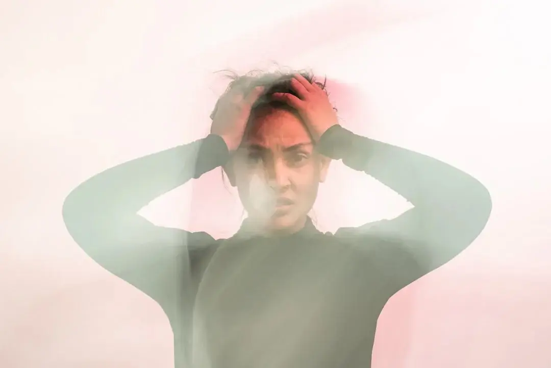A motion-blurred photograph of a person holding their head