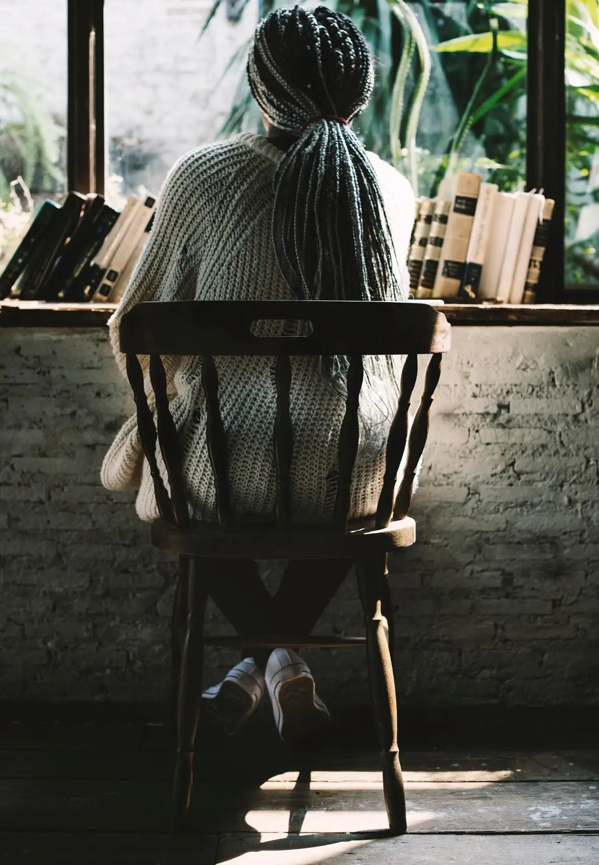 A person sitting alone on a chair, seen from behind