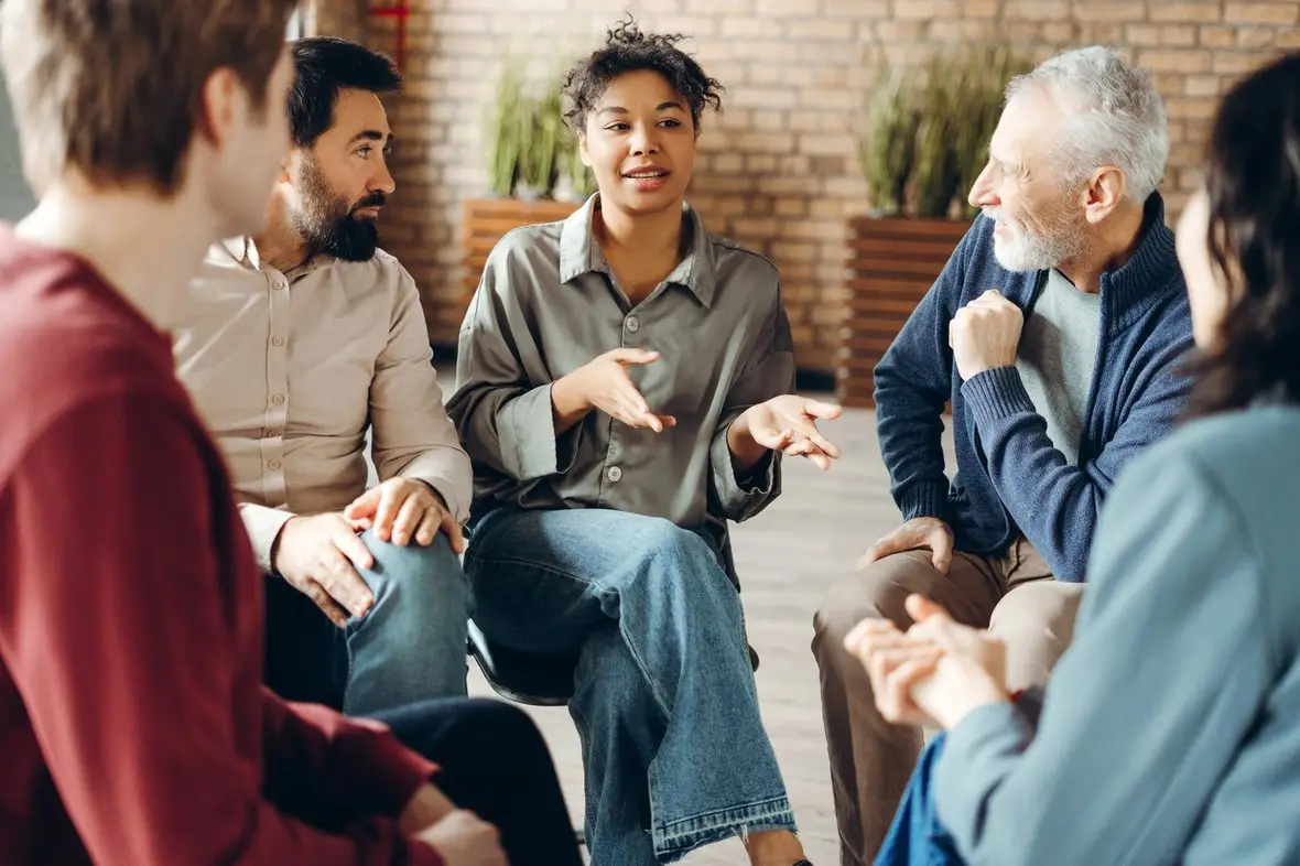 A group of people talking in a circle in a bright room
