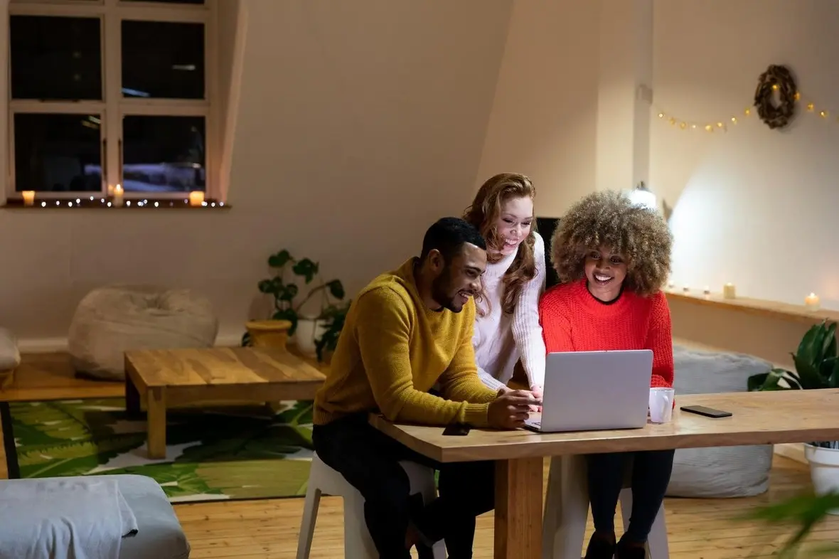 Friends looking at a laptop together in a warm room